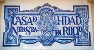 Fachada decorada con azulejos azules que muestran el nombre Casa Hermandad Nuestra Señora del Rocío con motivos ornamentales y religiosos en Morón de la Frontera