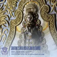Imagen de la Virgen del Rocío con vestimenta bordada en dorado y detalles florales, enmarcada por un fondo ornamental dorado